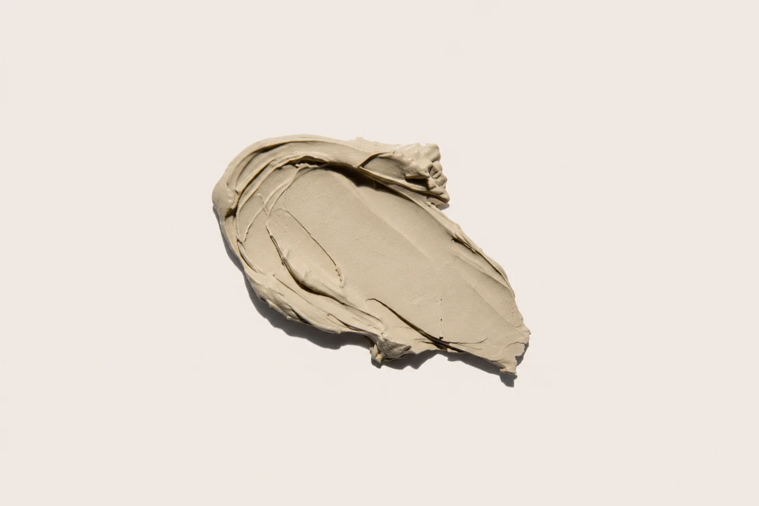 A smooth and textured smear of beige clay against a light background, showcasing its creamy and dense consistency.
