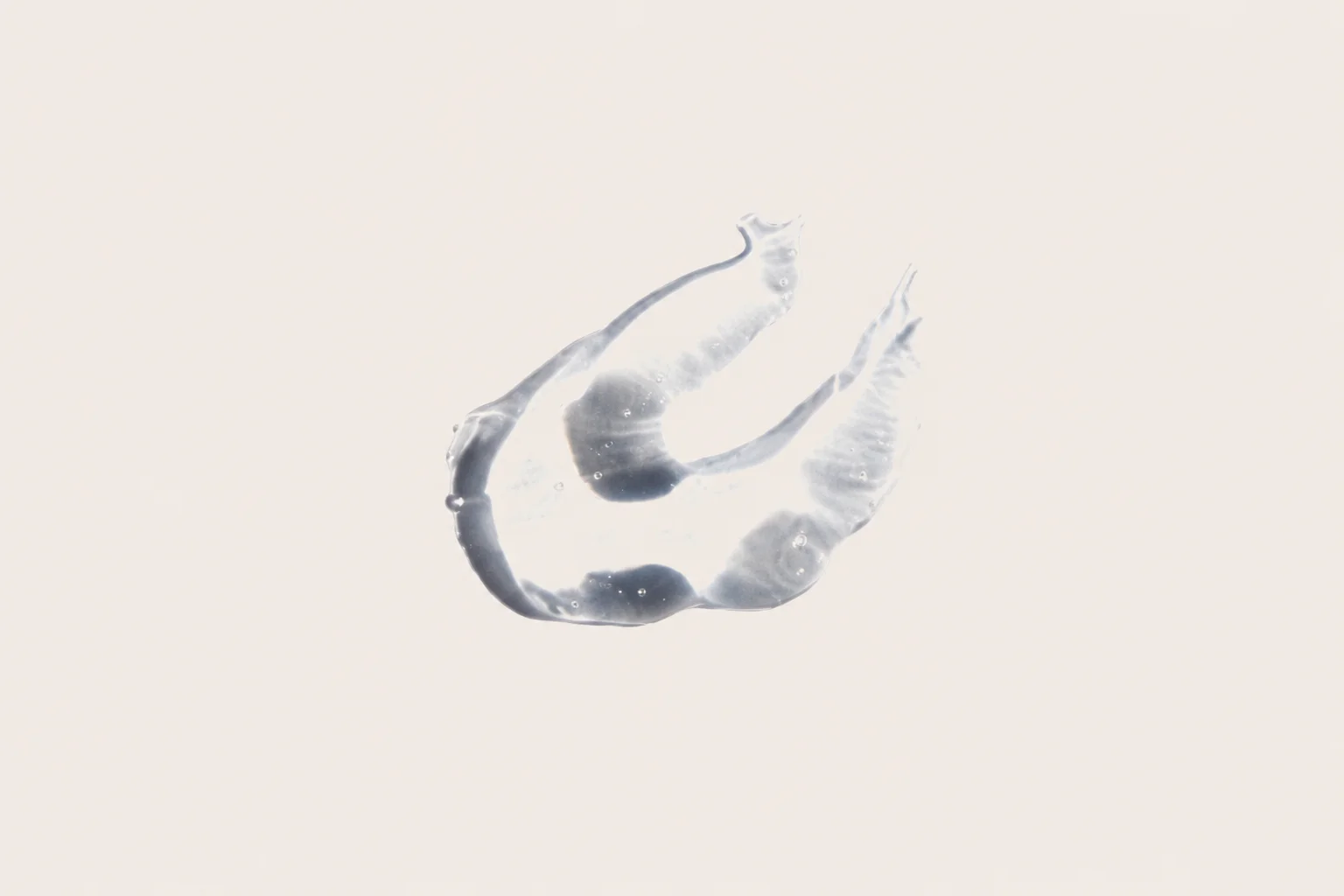 Transparent drop of gel with air bubbles on a white background, captured in close-up detail.
