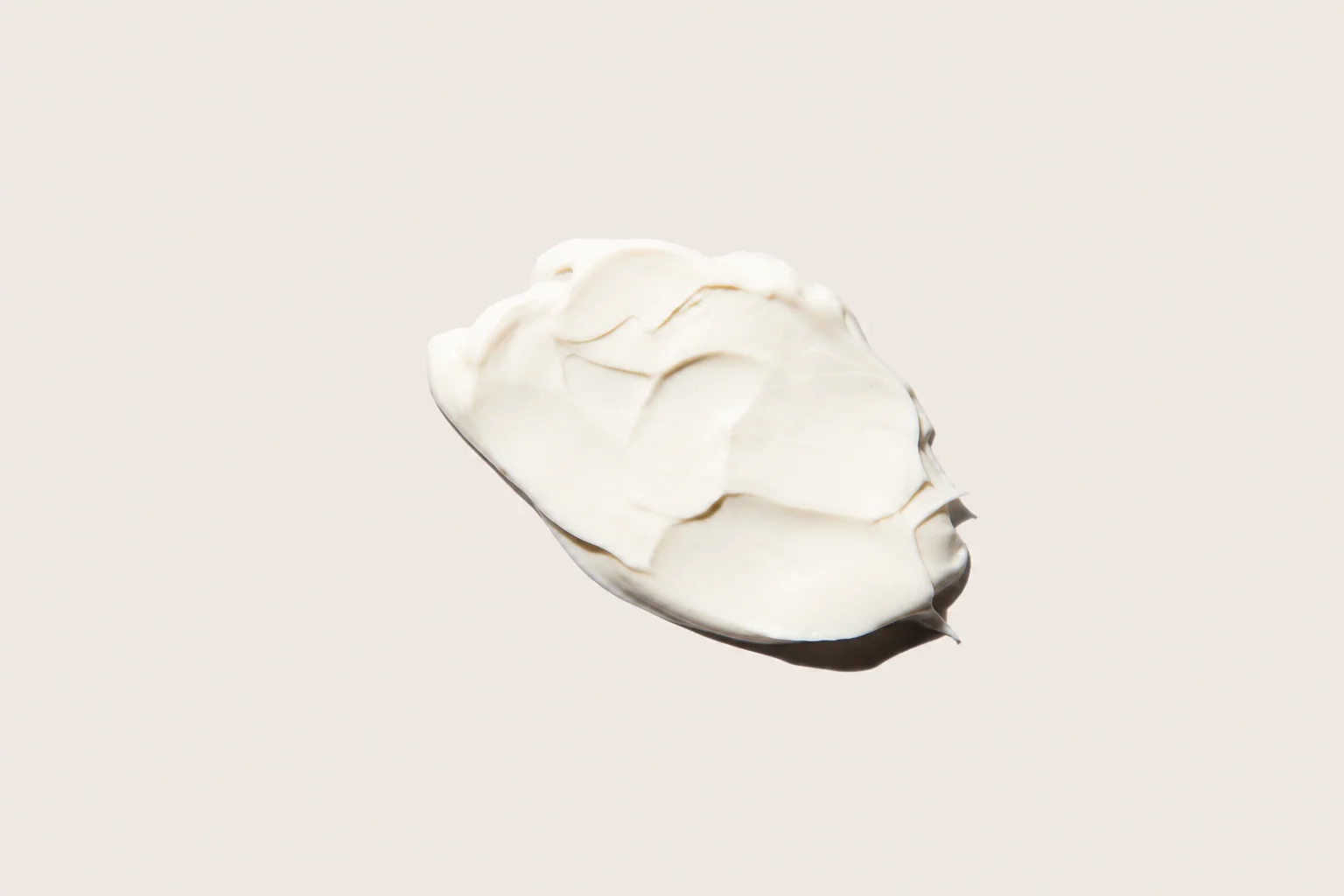 Close-up of a scoop of white cream balanced on the tip of a spoon against a plain background.